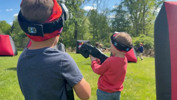 Two young players geared up with vests, headbands, and laser taggers at a backyard birthday party in Glen Mills, PA