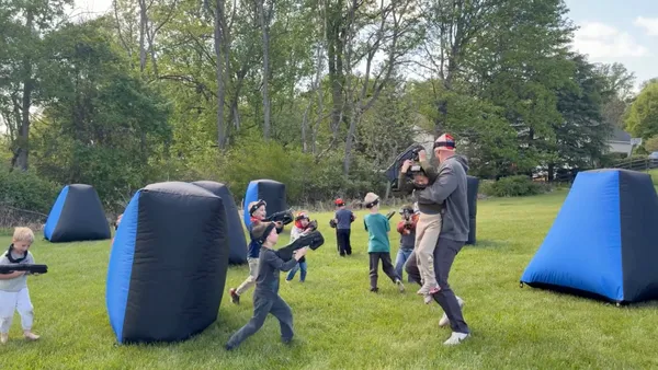 Dad swinging his son mid-game during a backyard mobile laser tag birthday party in Glen Mills, PA