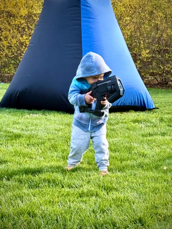 Tiny player gearing up with a pro-grade laser tagger to join the action at a backyard mobile laser tag party
