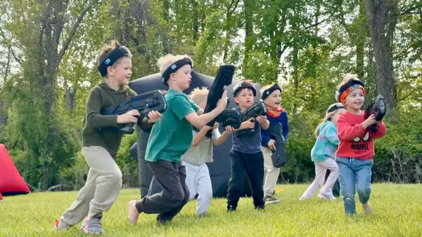 Group of kids charging across the yard at the start of a mobile laser tag battle in Glen Mills, PA