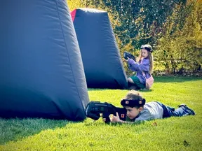 Kids ducking and crawling behind an inflatable bunker during an 8 year old's backyard laser tag birthday party