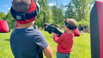 Two young players geared up with vests, headbands, and laser taggers at a backyard birthday party in Glen Mills, PA