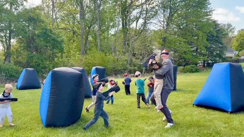 Dad swinging his son mid-game during a backyard mobile laser tag birthday party in Glen Mills, PA